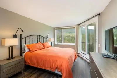 a bedroom with a bed and a tv and windows at 2112 The Pines Condo in Keystone