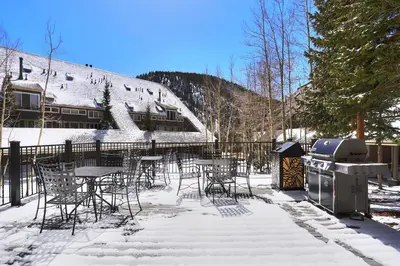 a grill and tables and chairs in the snow at 2112 The Pines Condo in Keystone