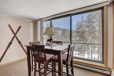a dining room with a table and chairs and a large window at 2065 The Pines Condo in Keystone