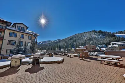 a patio with tables and benches in front of a mountain at 4368 Founders Pointe Cozy WP Village Condo in Winter Park