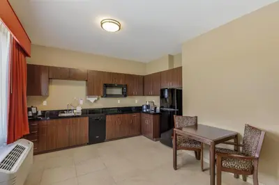 a kitchen with wooden cabinets and a table and chairs at Best Western Plus Hudson Hotel & Suites in Hudson