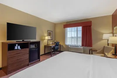 a hotel room with a bed and a flat screen tv at Best Western Plus Hudson Hotel & Suites in Hudson
