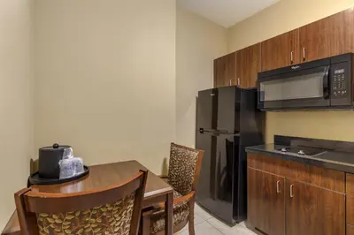 a kitchen with a table and a black refrigerator at Best Western Plus Hudson Hotel & Suites in Hudson