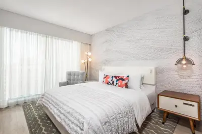 a white bedroom with a bed and a chair at Le Meridien Denver Downtown in Denver