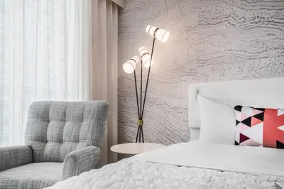 a bedroom with a bed and a chair and a lamp at Le Meridien Denver Downtown in Denver