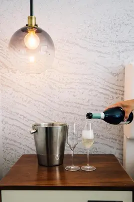 a person pouring wine into two glasses on a counter at Le Meridien Denver Downtown in Denver