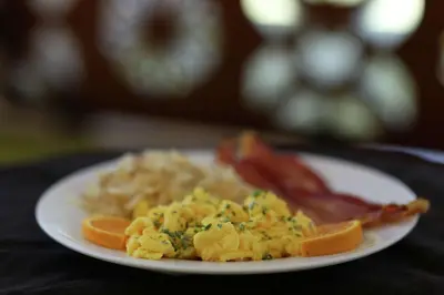 a plate of food with scrambled eggs and bacon at Hilton Garden Inn Arvada/Denver, CO in Arvada