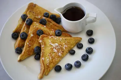 a white plate with blueberries and pancakes and a cup of coffee at Hilton Garden Inn Arvada/Denver, CO in Arvada