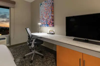 a room with a desk with a television and a chair at Hilton Garden Inn Arvada/Denver, CO in Arvada