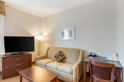 a hotel room with a couch and a table and a television at MainStay Suites Near Denver Downtown in Denver