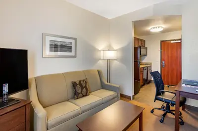 a living room with a couch and a desk and a kitchen at MainStay Suites Near Denver Downtown in Denver