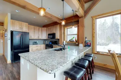 a kitchen with a granite counter top and a black refrigerator at Fraser Cabin in the Woods in Fraser