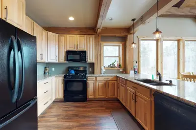 a kitchen with wooden cabinets and a black refrigerator at Fraser Cabin in the Woods in Fraser