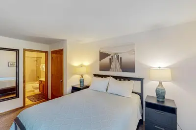a bedroom with a bed and two lamps and a bathroom at Buffalo Village Condo & Treetop Hideaway in Silverthorne