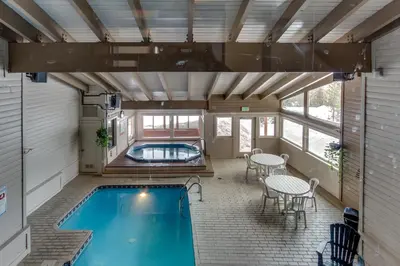 a swimming pool in a house with a table and chairs at Buffalo Village Condo & Treetop Hideaway in Silverthorne