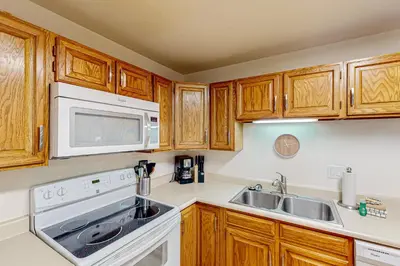 a kitchen with wooden cabinets and a sink and a microwave at Buffalo Village Condo & Treetop Hideaway in Silverthorne