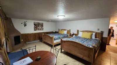 a room with two beds and a table and a tv at Kokopelli Inn in Estes Park