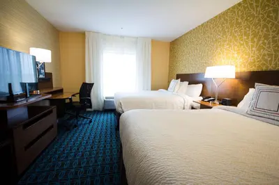 a hotel room with two beds and a flat screen tv at Fairfield Inn & Suites by Marriott Denver Northeast/Brighton in Brighton