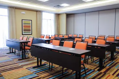 a conference room with tables and orange chairs at Fairfield Inn & Suites by Marriott Denver Northeast/Brighton in Brighton