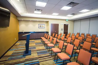 a conference room with orange chairs and a podium at Fairfield Inn & Suites by Marriott Denver Northeast/Brighton in Brighton