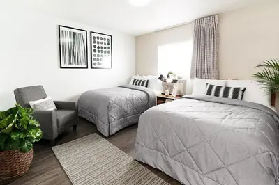 a bedroom with two beds and a chair at InTown Suites Extended Stay Denver - Havana Street in Aurora