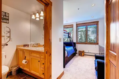 a bathroom with a sink and a mirror and a bed at Timbers 3077 in Keystone