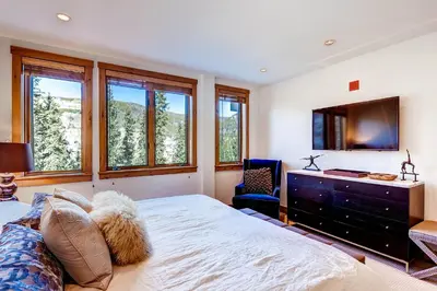 a bedroom with a bed and a tv and windows at Timbers 3077 in Keystone