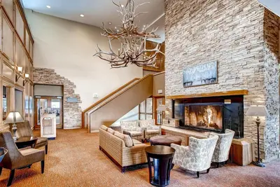 a living room with a large stone fireplace and a chandelier at Keystone Lodge & Spa, A Vail Resorts Property in Keystone