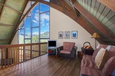 a living room with a vaulted ceiling with windows at Sky View in the Rockies in Estes Park