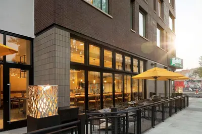a restaurant with tables and umbrellas in front of a building at Doubletree By Hilton Greeley At Lincoln Park in Greeley