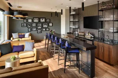 a bar in a restaurant with blue stools at Doubletree By Hilton Greeley At Lincoln Park in Greeley