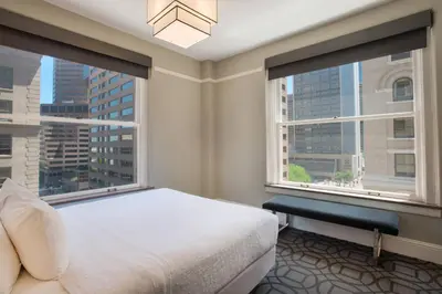 a bedroom with a bed and two large windows at Magnolia Hotel Denver, a Tribute Portfolio Hotel in Denver