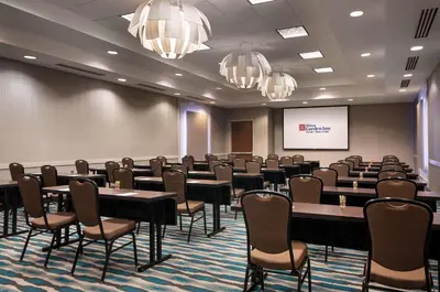 a conference room with tables and chairs and a screen at Hilton Garden Inn Denver/Cherry Creek in Denver