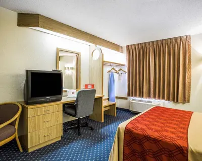 a hotel room with a bed and a desk with a television at Econo Lodge Denver International Airport in Aurora