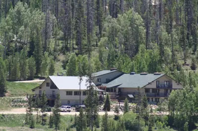 a large building in the middle of a forest at Hideaway Mountain Lodge in Fraser