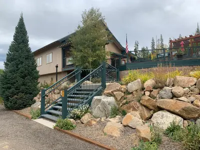 a house with a staircase in front of a pile of rocks at Hideaway Mountain Lodge in Fraser