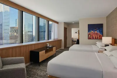 a hotel room with two beds and a chair and windows at Sheraton Denver Downtown Hotel in Denver