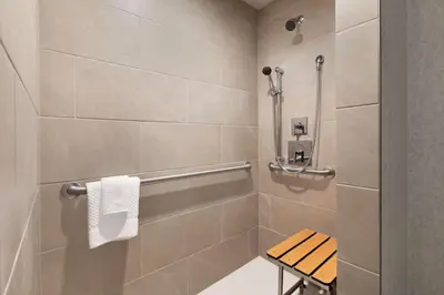 a bathroom with a shower with a bench in it at Embassy Suites By Hilton Boulder in Boulder