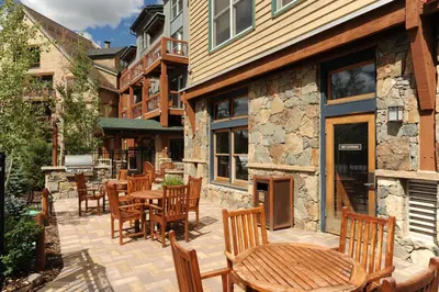 a patio with wooden chairs and tables and a building at Black Bear 8078 in Keystone