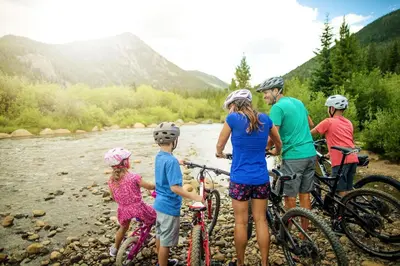 a group of people standing next to a river with bikes at Quicksilver 1643 in Keystone
