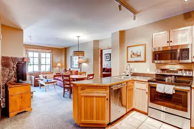 a kitchen with wooden cabinets and a living room at Dakota Lodge 8513 in Keystone