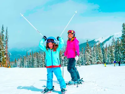 a woman and a child on skis in the snow at Expedition Station 8566 in Keystone