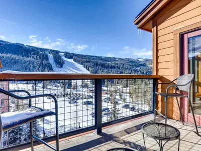a balcony with two chairs and a view of snow covered trees at Lenawee 1735 in Keystone
