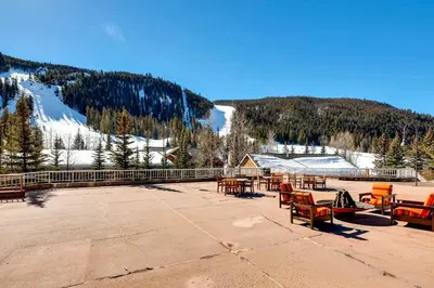 a patio with tables and chairs and a snow covered mountain at Slopeside 2741 in Keystone