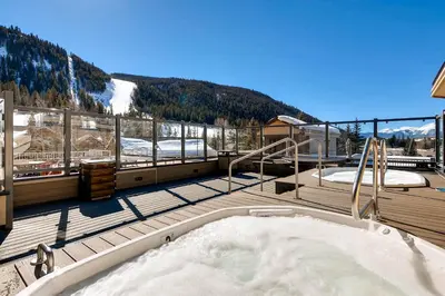 a hot tub on a deck with mountains in the background at Slopeside 2741 in Keystone