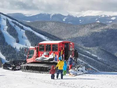 a group of people standing next to a snow truck in the snow at Red Hawk Lodge 2207 in Keystone