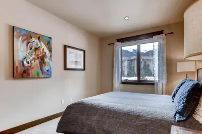 a bedroom with a bed and a painting of a horse on the wall at River Run Townhome RR37 in Keystone
