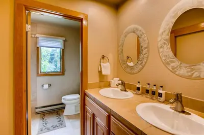 a bathroom with two sinks and a toilet and mirrors at Willows 1716 in Keystone