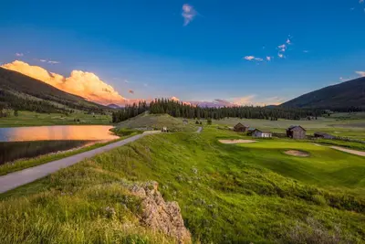 a view of a golf course with a lake and mountains at Buffalo Lodge 8325 in Keystone