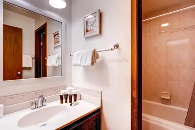 a bathroom with a sink and a mirror and a tub at Flying Dutchman 1210 in Keystone